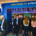 A group of professionally dressed people gather and walk through an entrance labeled Welcome to FBLA exhibit hall at a conference or event.